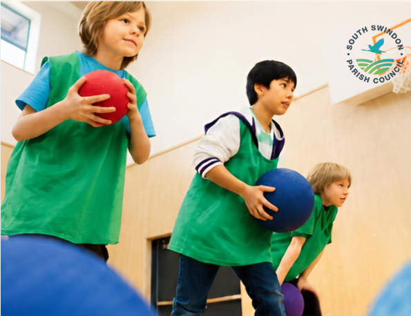 Children playing a ball game indoors, wearing green sports bibs and holding colourful balls.